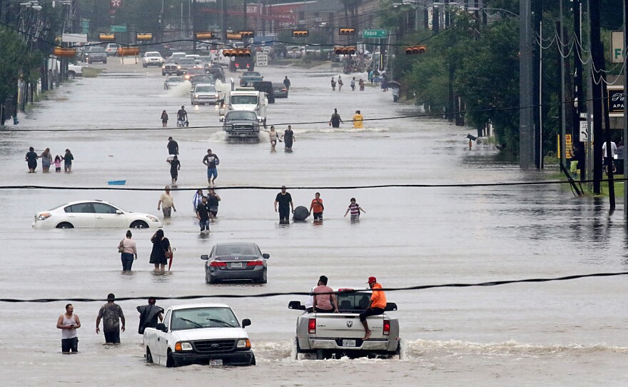 People walk through floodwaters on Telephone Road in Houston on Sunday after 2 feet of rain from Hurricane Harvey pummeled the Gulf Coast.
