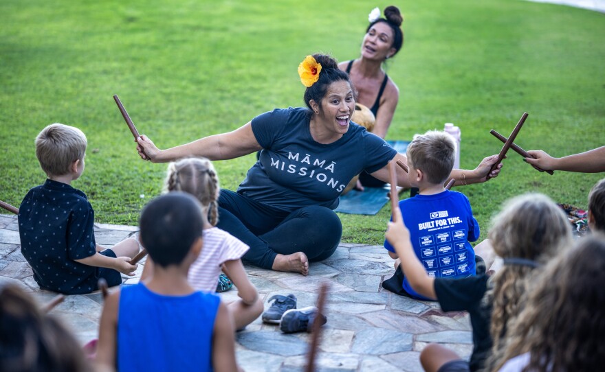 Leialoha Lani-Montira teaches a hula and music class. Yoga teacher, Kilihune Ka'aihue is behind her playing an ipu.