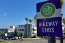 A sign reads "Go by bike — bikeway ends" as a cyclist rides past on Robinson Avenue, Sept. 17, 2026.