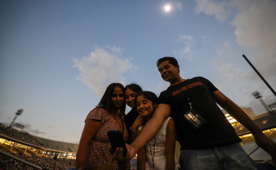 Mindy and Jas Gill take photos with daughter Jaclyn, 15, and Jasmine, 10 during the totality during the eclipse event at Cotton Bowl stadium in Dallas.