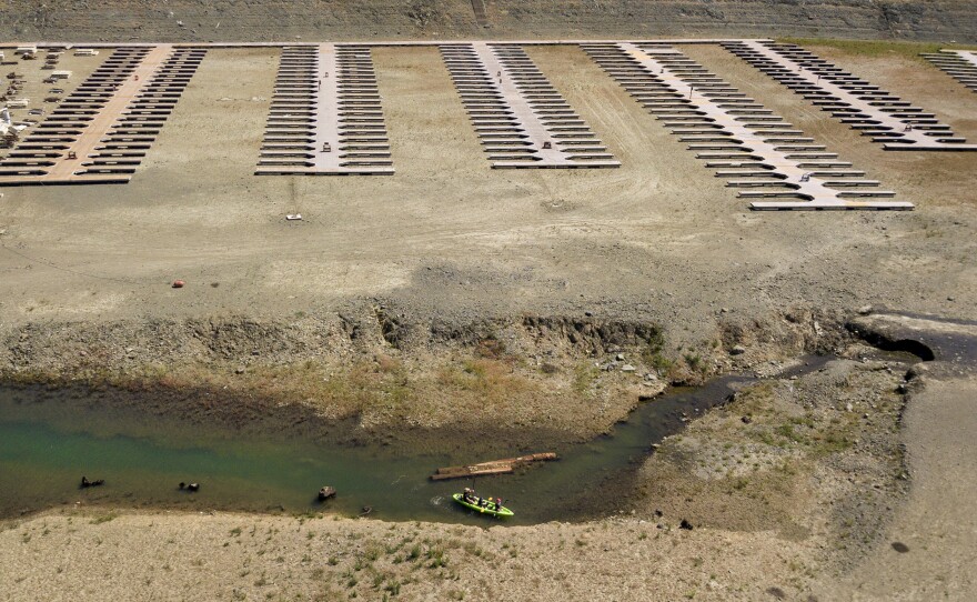 Kayakers navigate a narrow section of water near boat docks sitting on dry land at the Browns Ravine Cove area of drought-stricken Folsom Lake, in Folsom, Calif., Saturday, May 22, 2021. California Gov. Gavin Newsom threatened Monday, May 23, 2022, to impose mandatory, statewide restrictions on water use if people don't start using less on their own as the drought drags on and the hotter summer months approach.