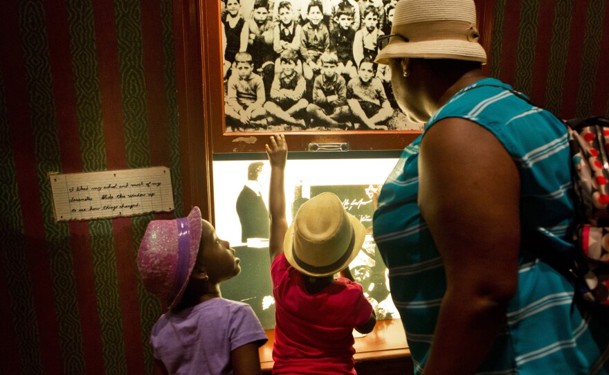 (Top left) A loaf of bread that Daniel's family ate for their meals while they lived in the ghetto. (Top right) Aiden reads one of Daniel's diary entries. Twin sisters Nicolette and Victoria Dejour, 6, look through a window displaying scenes of Germany with their mother Royanne in the children's exhibit at the Holocaust Museum in Washington D.C.