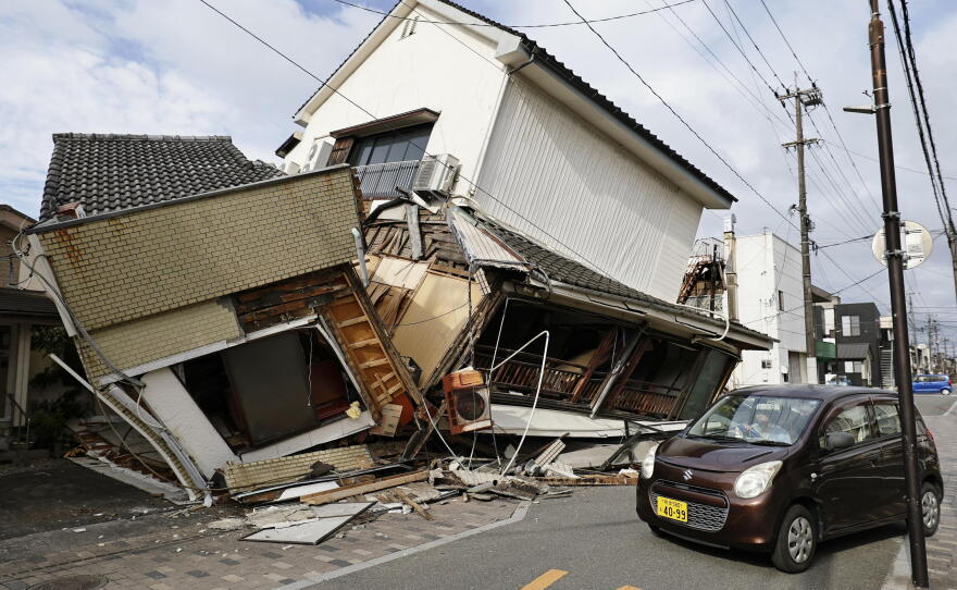 A vehicle passes by collapsed houses after an earthquake in Yatsushiro, Kumamoto prefecture, Wednesday, July 29, 2026.