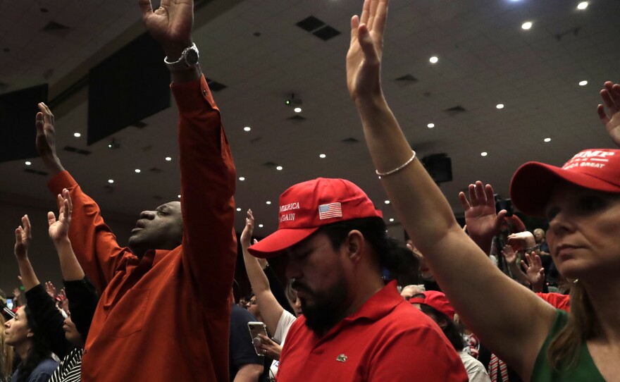 People raise their arms in prayer during a rally for evangelical supporters of President Donald Trump at the King Jesus International Ministry church on Jan. 3, 2020, in Miami.