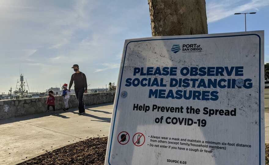 A sign reminding people of socially distance during the COVID-19 pandemic at Tuna Harbor Park at the Embarcadero in downtown San Diego on Dec. 13, 2020.