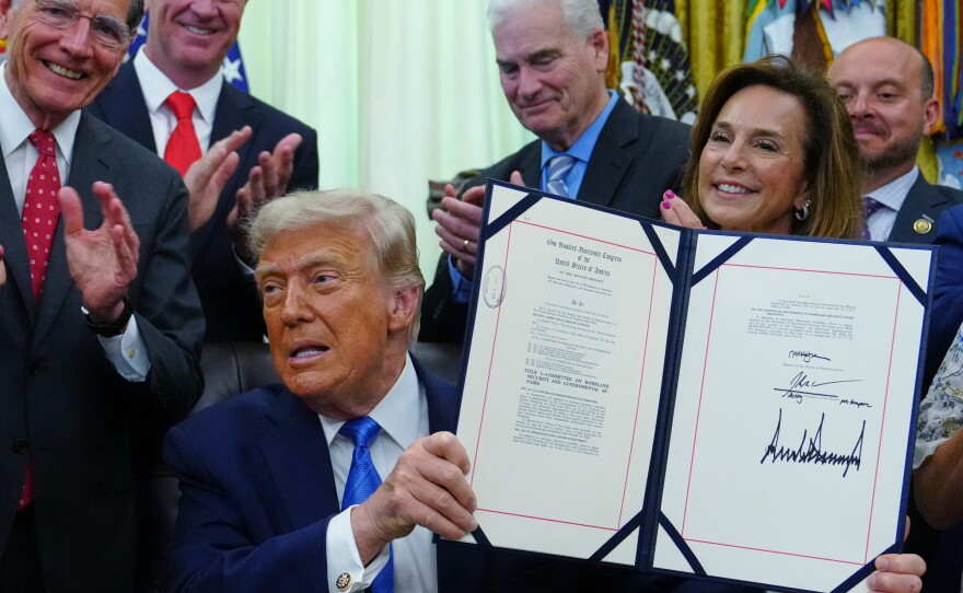 President Trump holds up a bill funding immigration enforcement after signing it in the Oval Office of the White House, Wednesday, June 10, 2026, in Washington.