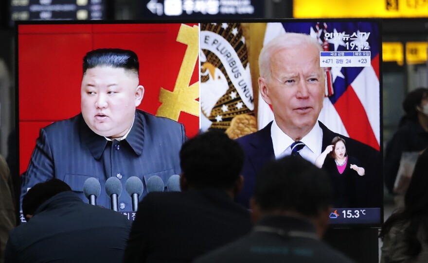 Commuters watch a TV showing a file image of North Korean leader Kim Jong Un and U.S. President Joe Biden at the Suseo Railway Station in Seoul, South Korea, on March 26, 2021.