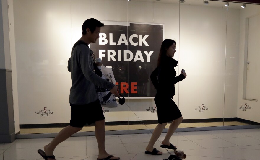 Shoppers walk past a Saks Fifth Avenue outlet store in Miami on Black Friday. Millennials have lower earnings, fewer assets and less wealth, a new Federal Reserve study says.