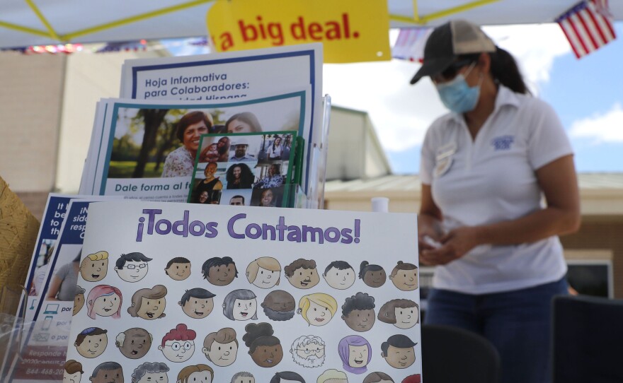 U.S. Census Bureau worker Marisela Gonzales stands by a display of books and flyers about the 2020 census at a walk-up counting site in Greenville, Texas, in July. The bureau's employees are under a time crunch to try to complete the national head count after the agency announced that counting will end a month early.