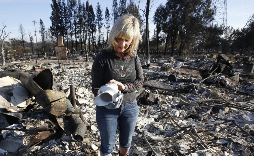 Debbie Wolfe looks at the antique pitcher that once belonged to her grandmother after finding it in the burned ruins of her home in Santa Rosa, Calif. in this undated photo.