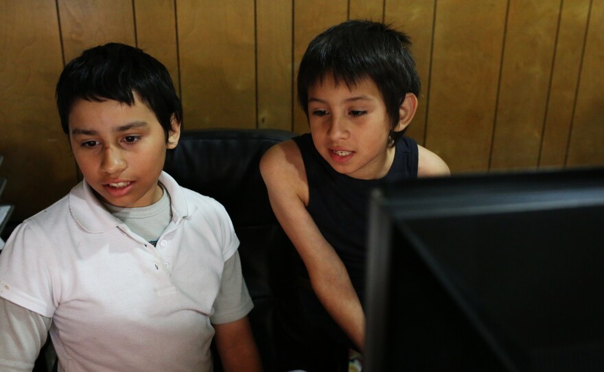 Fernanda and Robert Sandoval play games on their fathers computer while he finishes his workday, April 21, 2016.