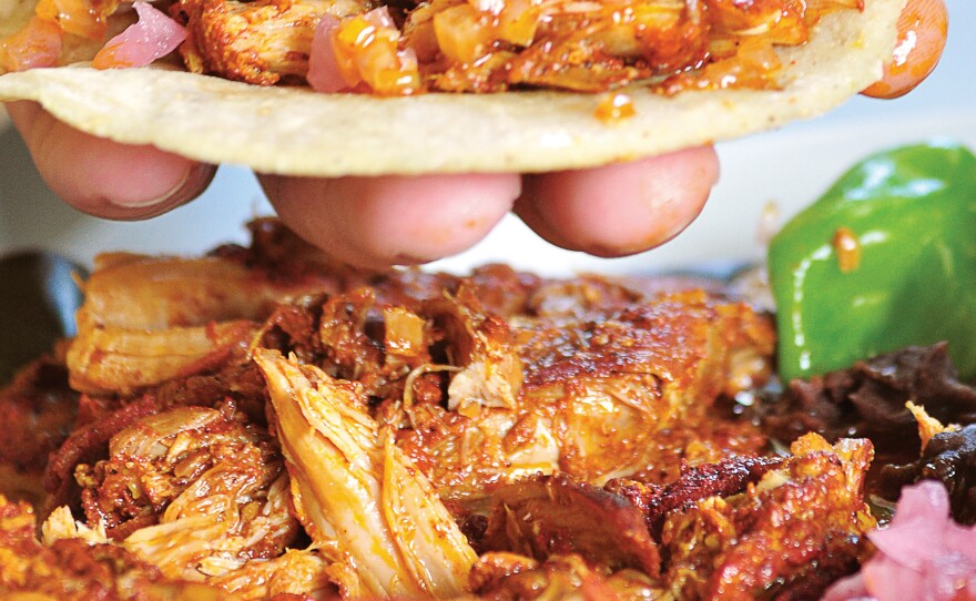 The name of these tacos, "cochinita pibil," tells you what's inside: young pig cooked in an oven pit. It's a traditional Mayan dish that originated after the Spanish conquistadors arrived, bringing pigs with them.
