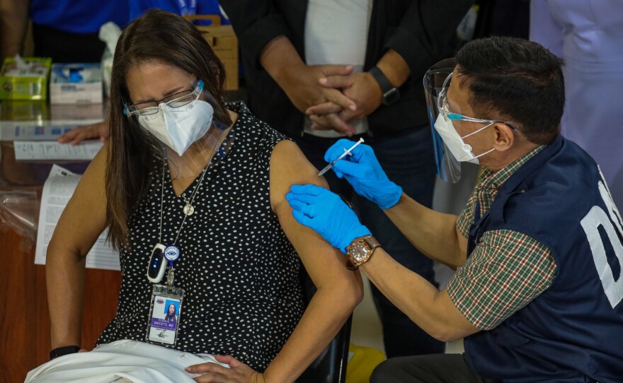 Philippines Health Secretary Francisco Duque III (R) administers the China-made Sinovac vaccine against the Covid-19 coronavirus disease to Eileen Aniceto, a doctor at the Lung Center of the Philippines.