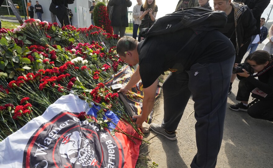 A fighter of the Wagner private military force places a sledgehammer, one of the Wagner symbols, at an informal memorial next to the former Wagner headquarters in St. Petersburg, Russia, Thursday.