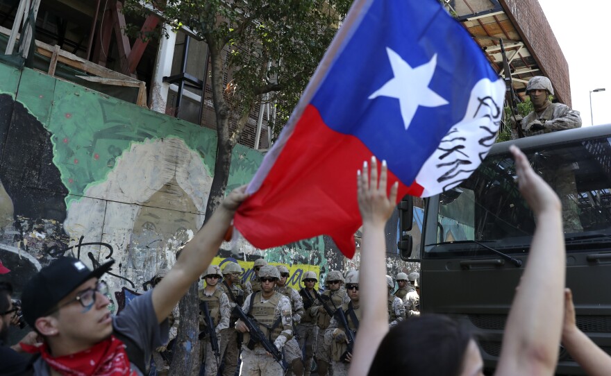 Protesters wave a Chilean national flag in front of military personnel in Santiago on Monday.