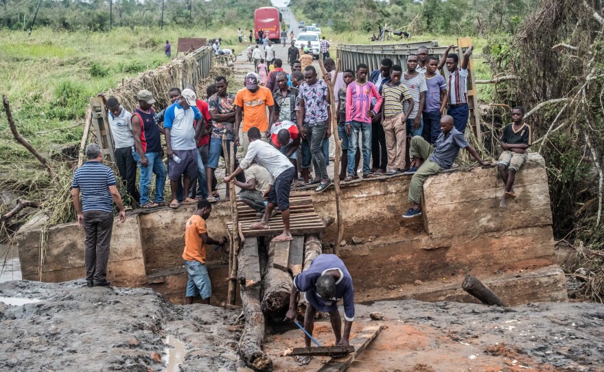 After the cyclone knocked out a bridge in Macomia, people worked to build a makeshift replacement out of logs and planks.