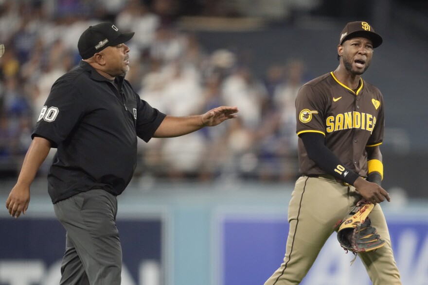 San Diego Padres left fielder Jurickson Profar, right, talks to umpire Adrian Johnson after items were thrown at Profar in the outfield during the seventh inning in Game 2 of a baseball NL Division Series against the Los Angeles Dodgers, Sunday, Oct. 6, 2024, in Los Angeles.