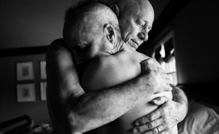 Dad and Mom embrace in the bedroom of their home. They never could have imagined both being in treatment for cancer at the same time. Together, they faced the daily struggles of illness in their own lives while also caring for each other.