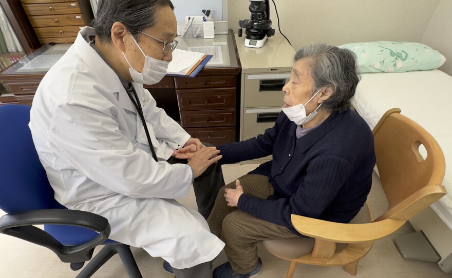 Dr. Masao Tomonaga takes the pulse of an atomic bomb survivor at a care home in Nagasaki, Japan.