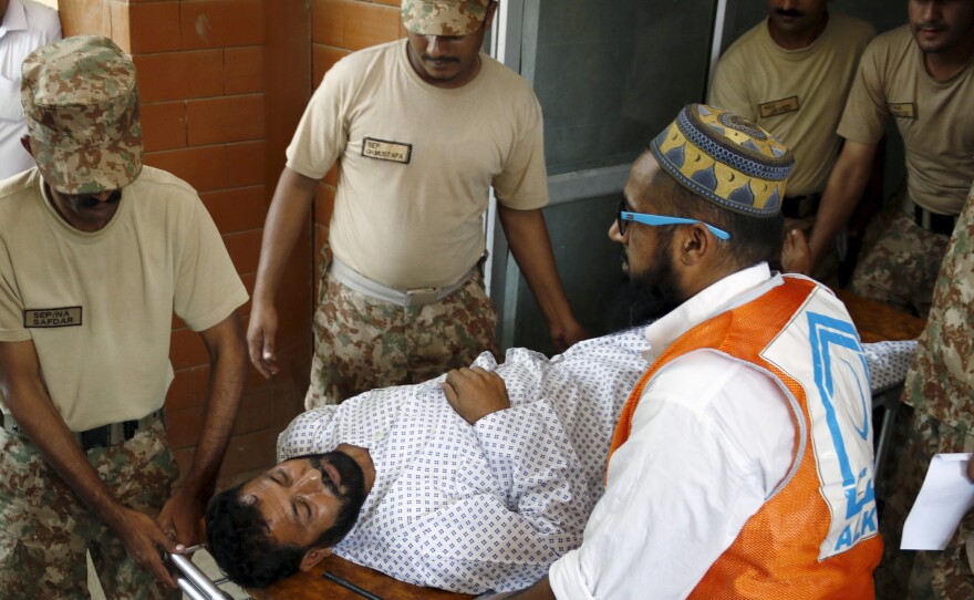 Soldiers help emergency workers wheel an injured man to a hospital after an attack by Taliban militiamen on an air force base in Peshawar, Pakistan, on Friday.