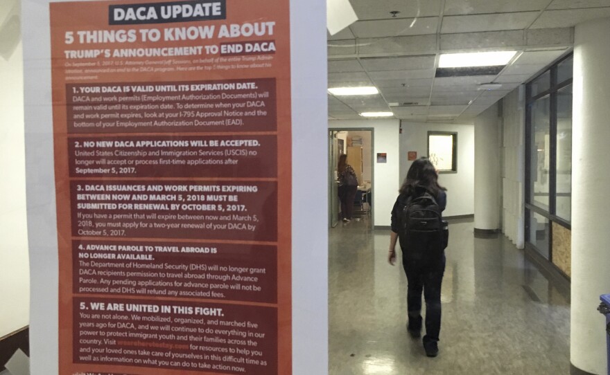 A student walks past a tip sheet for Deferred Action for Childhood Arrivals recipients who fear deportation that is taped to a window on the University of California, Berkeley campus in Berkeley, Calif., Sept. 7, 2017. 