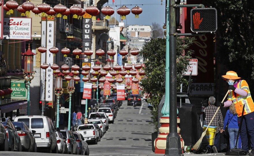 In this Jan. 31, 2020, file photo, a masked worker cleans a street in the Chinatown district in San Francisco. Police and volunteers have increased their street presence after a series of violent attacks against older Asian residents in Bay Area cities stoked fear and subdued the celebratory mood leading up to the Lunar New Year. (AP Photo/Ben Margot, File)