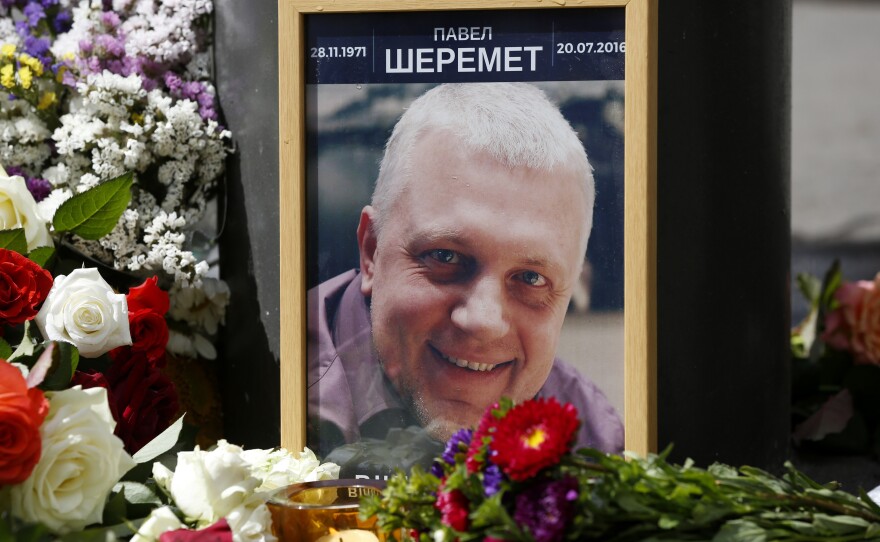 A portrait of journalist Pavel Sheremet is surrounded with flowers and candles near where he was killed.