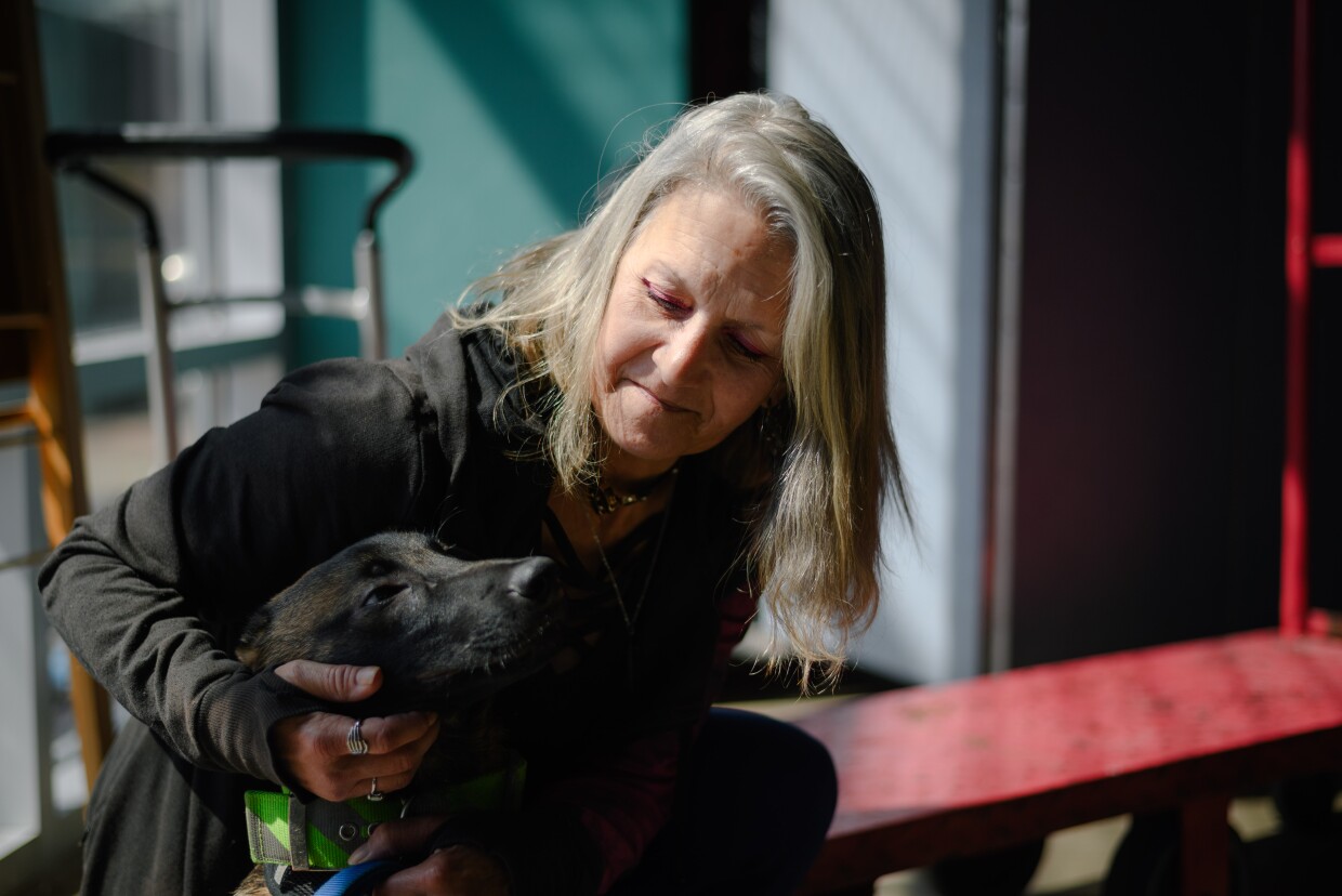 Rachel Hayes kneels for a portrait with her dog, Shilo, at Living Water Church of the Nazareth, the inclement weather shelter in downtown San Diego where she volunteers, on March 13, 2024. Hayes is a formerly unhoused advocate who has been living in permanent supportive housing since June 2023.