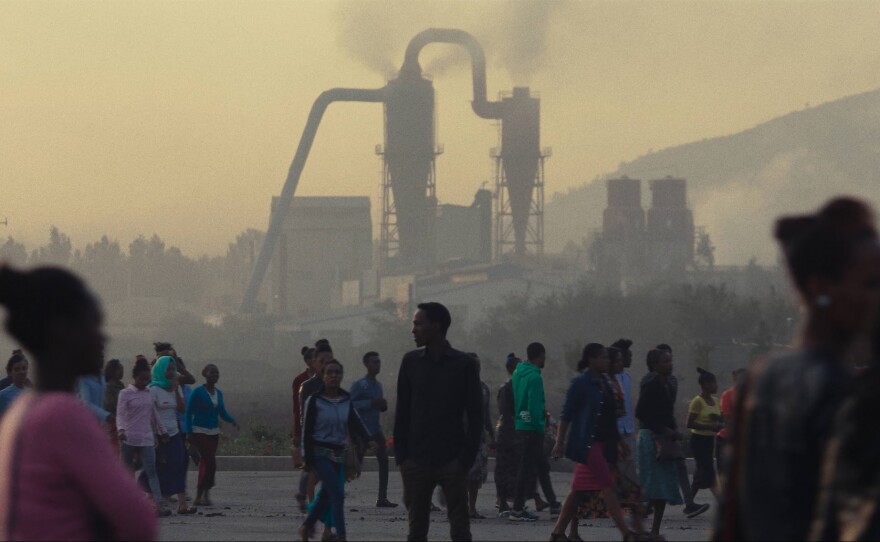 Factory workers walk in front of the chimney of a steel plant on their way to work at the Eastern Industry Park, Oromia Region, Ethiopia.