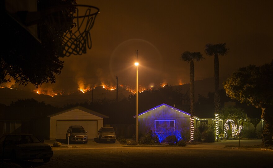 Christmas decorations illuminate a house as the growing Thomas Fire advances toward Santa Barbara County seaside communities.