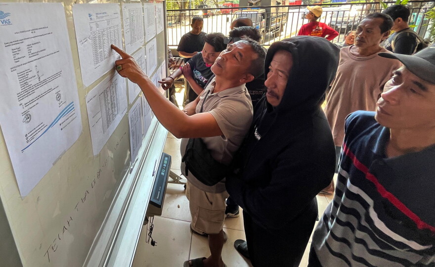People check the passenger manifest of Virgo Transport 8 passenger ferry which overturned in bad weather in the Java Sea, at the rescuers' command center in Banjarmasin, South Kalimantan, Indonesia, Monday, Sept. 14, 2026.