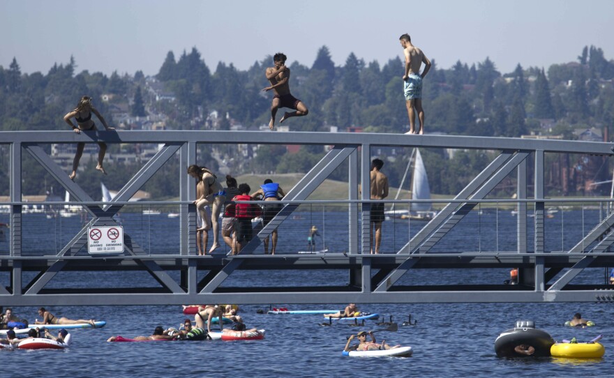 People jump from a pedestrian bridge at Lake Union Park in Seattle on Sunday as a record-setting heat wave blasts the Pacific Northwest.