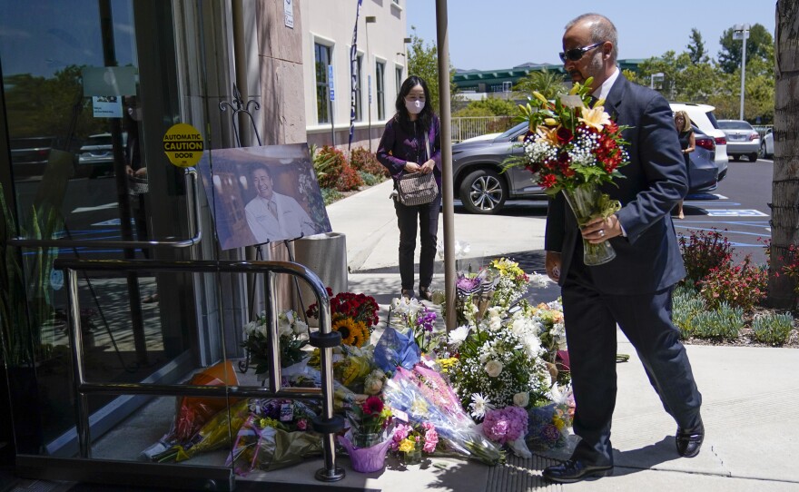 A man places flowers at a memorial honoring Dr. John Cheng outside his office building on Tuesday in Aliso Viejo, Calif. Cheng, 52, was killed in Sunday's shooting at Geneva Presbyterian Church.
