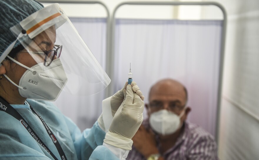 As part of a clinical trial in Peru, a health worker prepares to inoculate a volunteer with a COVID-19 vaccine produced by the Chinese company Sinopharm.