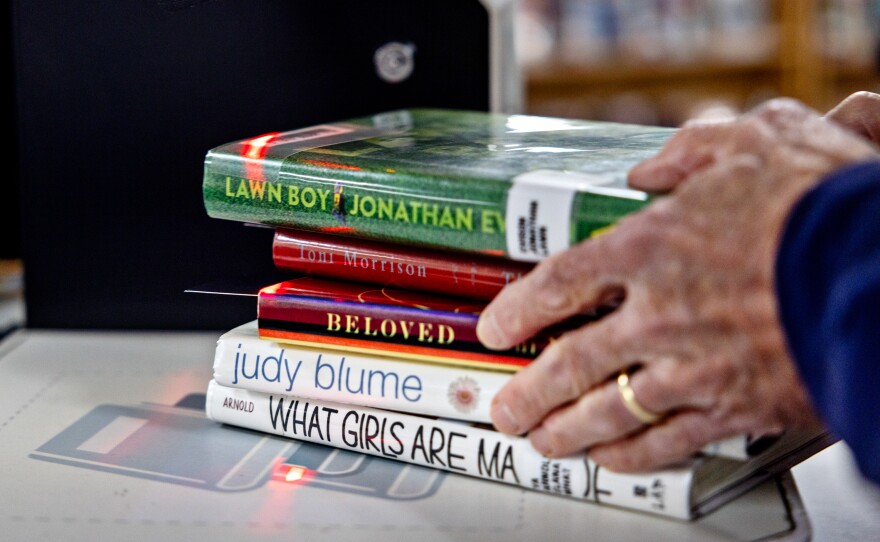 Parents Against Bad Books co-founder Tom Harrison grabs a stack of what group members call age-inappropriate books that they checked out from the Idaho Falls Public Library on Oct. 4.