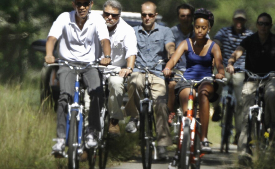President Obama and his daughter Malia ride bicycles along a path on Martha's Vineyard, Mass., in August 2010. Obama is returning to the island for his vacation this summer.