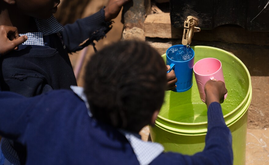 Students at Saint Juliet's fill their cups with water during a break from their exams.<strong> </strong>The water flows out a machine, developed by a company called Majik Water, that pulls water out of the air through a condensation technique.