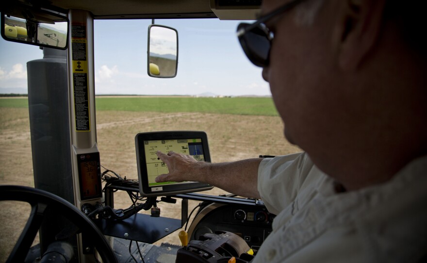 Buffett rides in a tractor to show how crops are planted using GPS technology.
