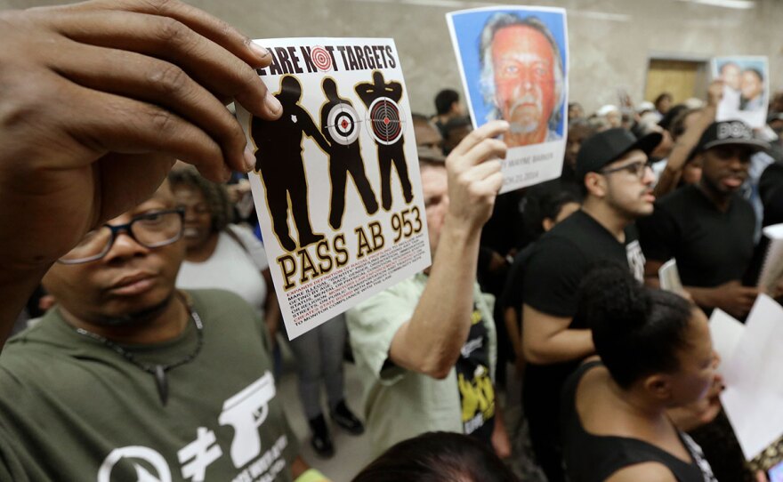 Protestors shouting "black lives matter" hold up photos of people they claim are the victims of police violence as they block the hallway outside the governors office while successfully demanding the passage of AB953, in Sacramento, Calif.,  Sept. 2, 2015.