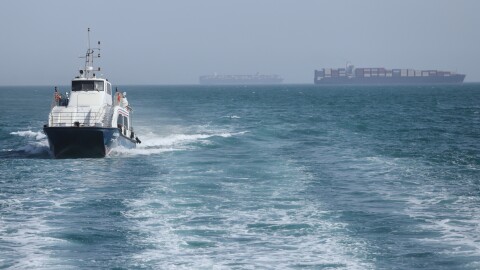 A patrol boat moves through the water as cargo ships sit at anchor in the Strait of Hormuz off Bandar Abbas, Iran, Saturday.