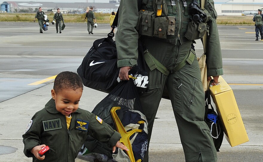 Lt. Cmdr. Chris Singletary, assigned to the Chargers of Helicopter Anti-Submarine Squadron (HS) 14, walks with his son on the flight line during a homecoming celebration. HS-14 completed a deployment aboard the aircraft carrier USS George Washington (CVN 73).