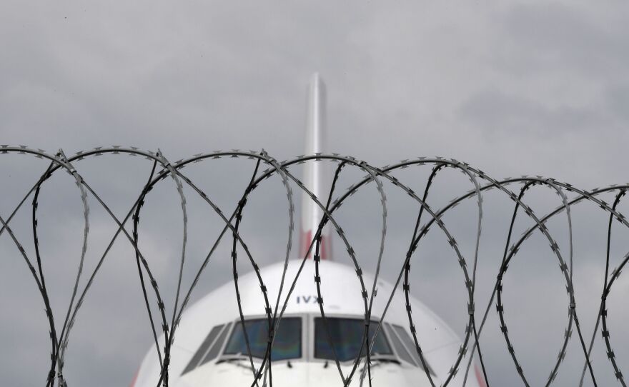 A British Airways plane sits parked behind a fence last month at London's Heathrow Airport. An association of major British airlines expects the U.K. government to roll out quarantine restrictions to combat the coronavirus, though confirmed details remain unclear.