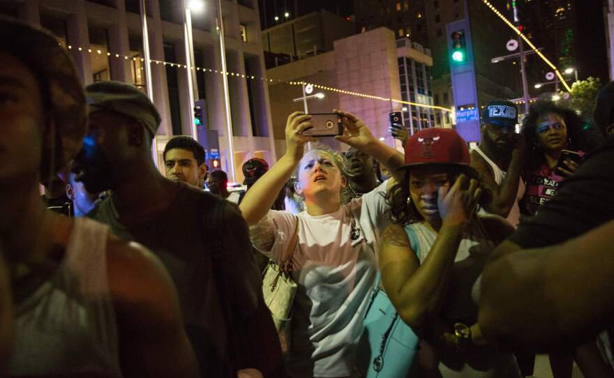 Protestors react as police officers arrest a bystander in downtown Dallas following Thursday's shooting.