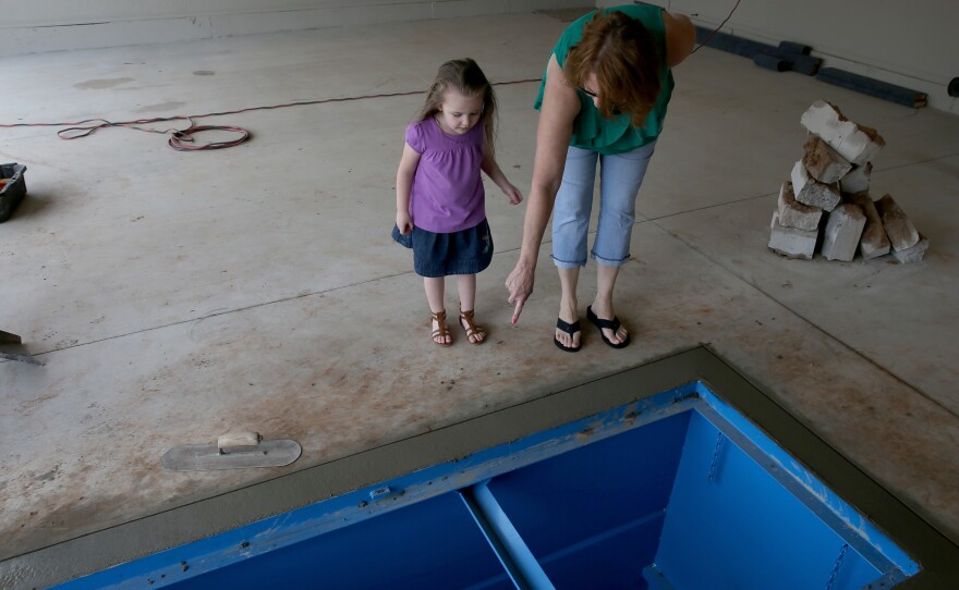 A woman shows her granddaughter the newly installed tornado shelter in the floor of the garage in 2014 in Moore, Okla.