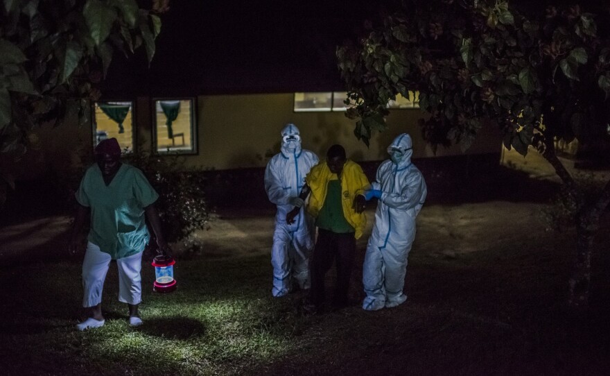 Health workers at an Ebola treatment center, run by Doctors Without Borders, greet man whose family brought him in by wheelbarrow. They suspected that he had the virus. The center is in Foya, Liberia.