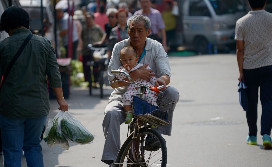 Faced with an aging population, China has eased its one-child policy. Here, an elderly man is seen holding a baby as he rides a bicycle in Beijing last month.