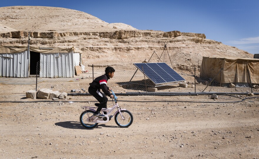 A boy rides a bicycle in a Bedouin camp receiving mobile health treatment. Mental health care providers say they worry about the toll that the war in Gaza, as well as settler violence, is having on West Bank residents — children in particular.