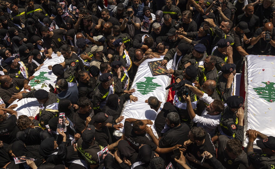 Fellow paramedics, dressed in uniform, carry their colleagues' coffins, draped with Lebanese flags, on their shoulders as mourners gather and weep in southern Lebanon on April 30, 2026.