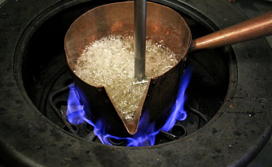 The simple mixture of corn syrup, sugar and water is brought to a boil in an antique pot on a candy stove from the 1920s.