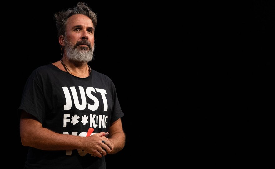 Manuel Oliver is shown on stage in an undated photo. He wears a black shirt that says "Just F***ing Vote."